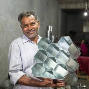 A man, Anwar Saleem, holding up a metal tray in a factory.