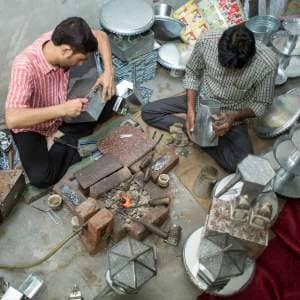 Two men, including Anwar Saleem, are working on a table in a workshop.