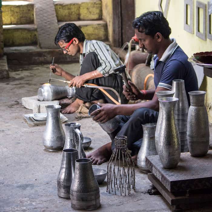 About Us: A group of men crafting vases in a workshop.