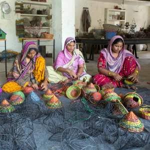 A group of women are crafting baskets in a workshop, inspired by Intizar Hussain.