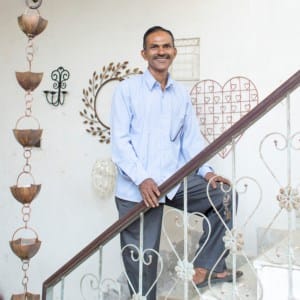 A man named Kamrul Hasan standing on a stair railing in India.