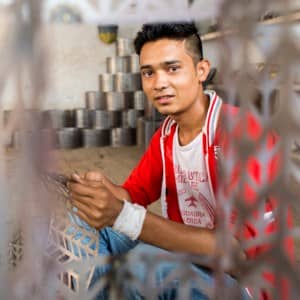 Kamrul Hasan, a young man working in a metal shop.