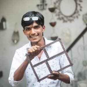 A young man named Kamrul Hasan holding up a piece of cardboard.
