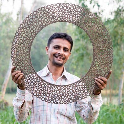 A man holding up a circular metal frame in his home.