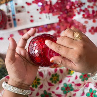 A woman is holding a red ornament at home.