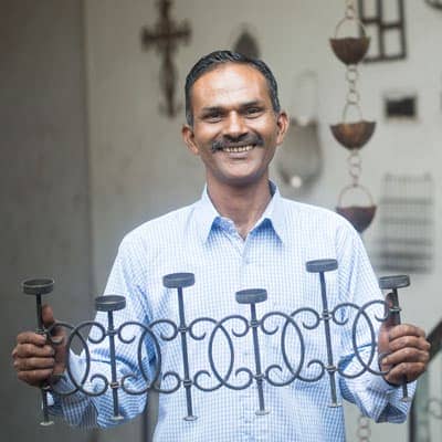 A man holding up a set of iron railings outside his home.
