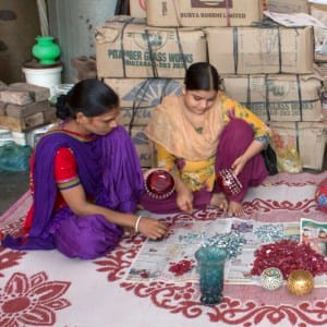 A group of women sitting on a rug during a gathering.