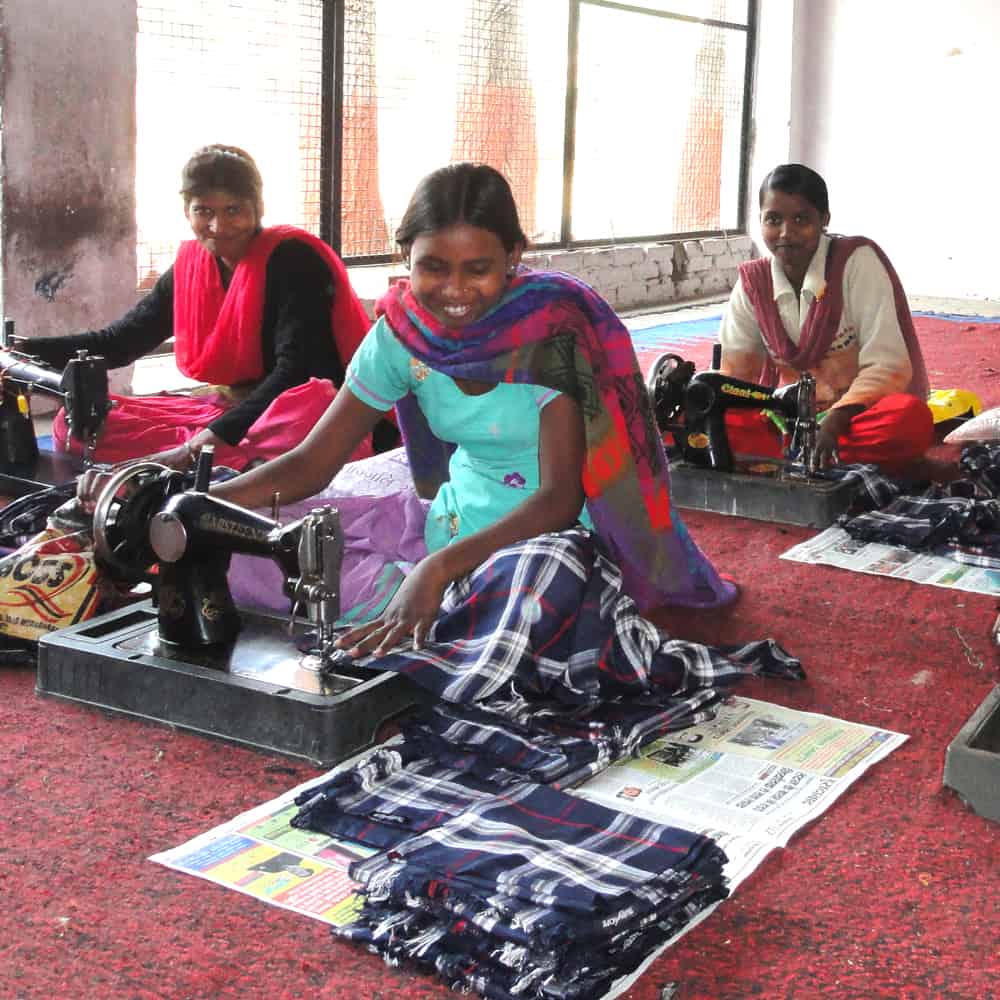 Women working on sewing machines in a room as part of Project Disha.
