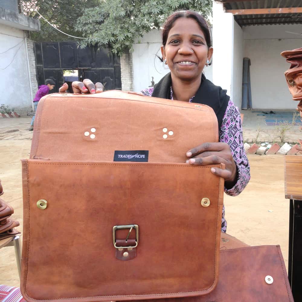 A woman holding up a brown leather briefcase for Project Disha.