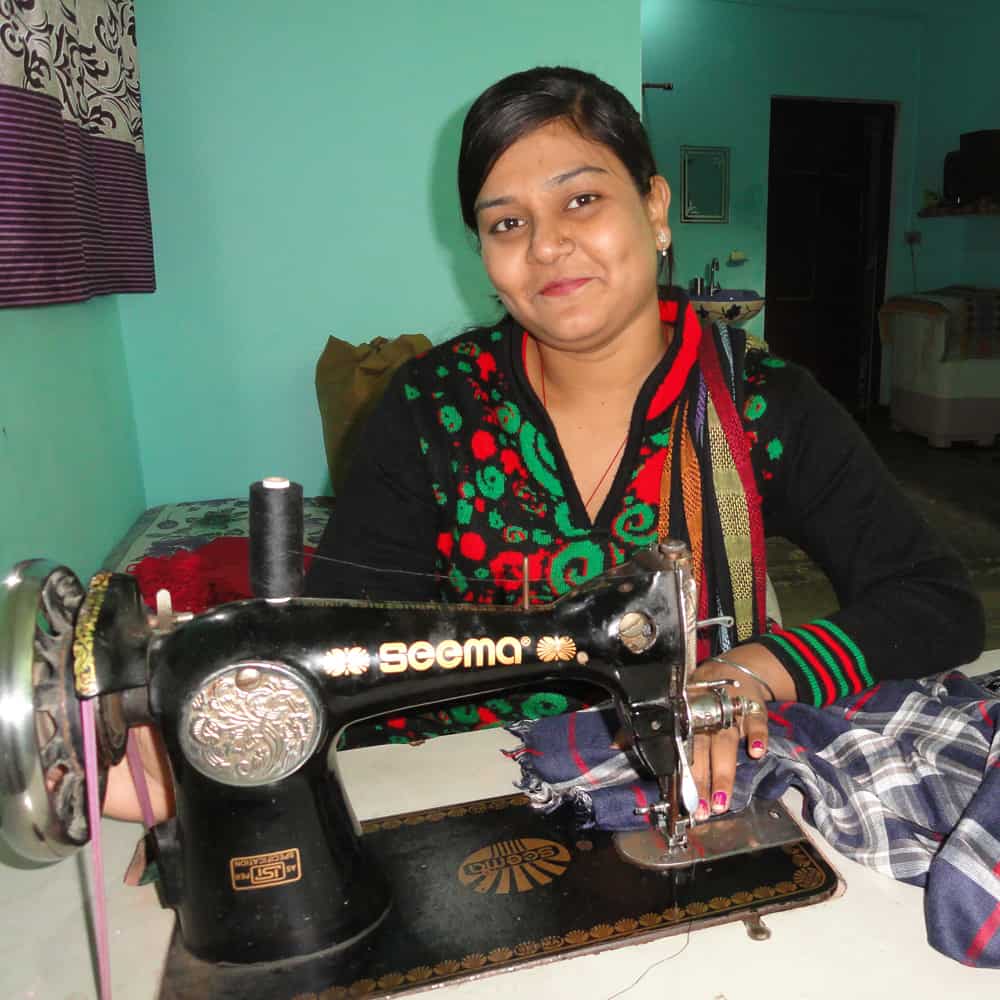 A woman sewing on a sewing machine as part of Project Disha.
