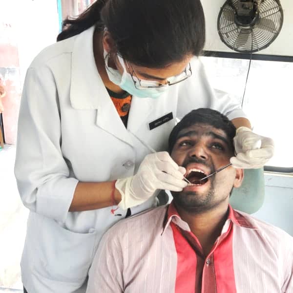 A man undergoes a dental check-up at a health camp.