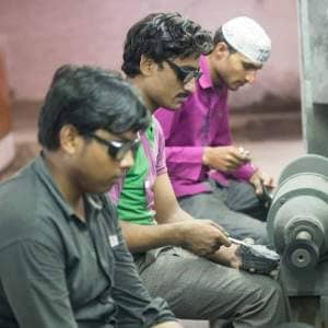 A group of men, including Dilshad Hussain, working on a machine in a factory.