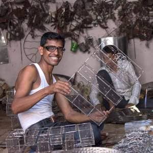A man named Khalil Ahmed working in a workshop with a lot of metal pieces.