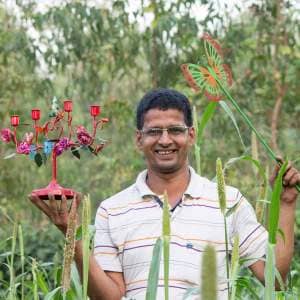 A man named Khalil Ahmed standing in a field surrounded by plants.