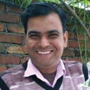 Khalil Ahmed is smiling while holding a trophy.