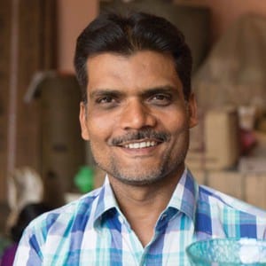 A man named Khalil Ahmed smiling while holding a blue vase.