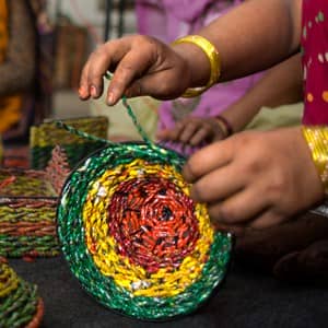 A group of women making baskets out of recycled materials at home.