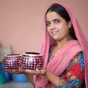 A woman at home holding two glass vases.