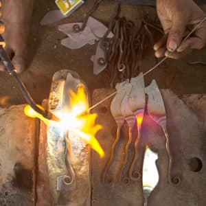 A man is working on a piece of metal at home with a torch.