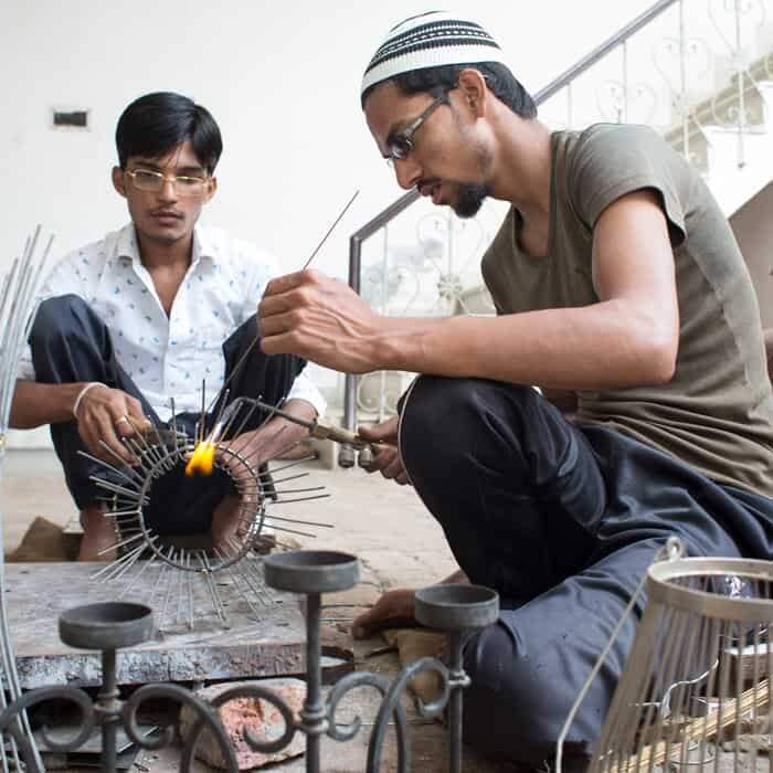 Two men, including Kamrul Hasan, working on a piece of metal.